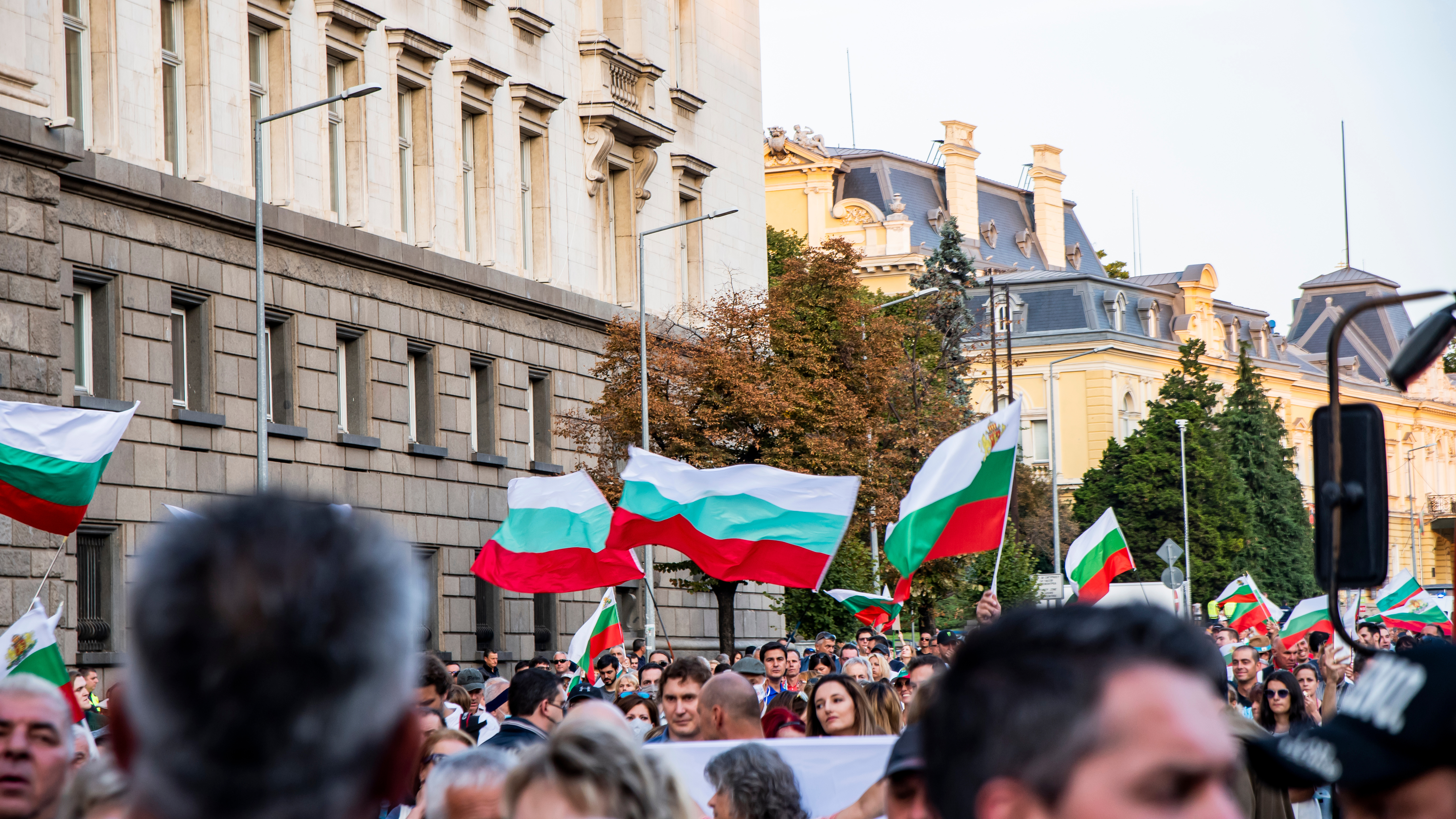 Беженцы держат флаги Болгарии, которая предоставляет им убежище