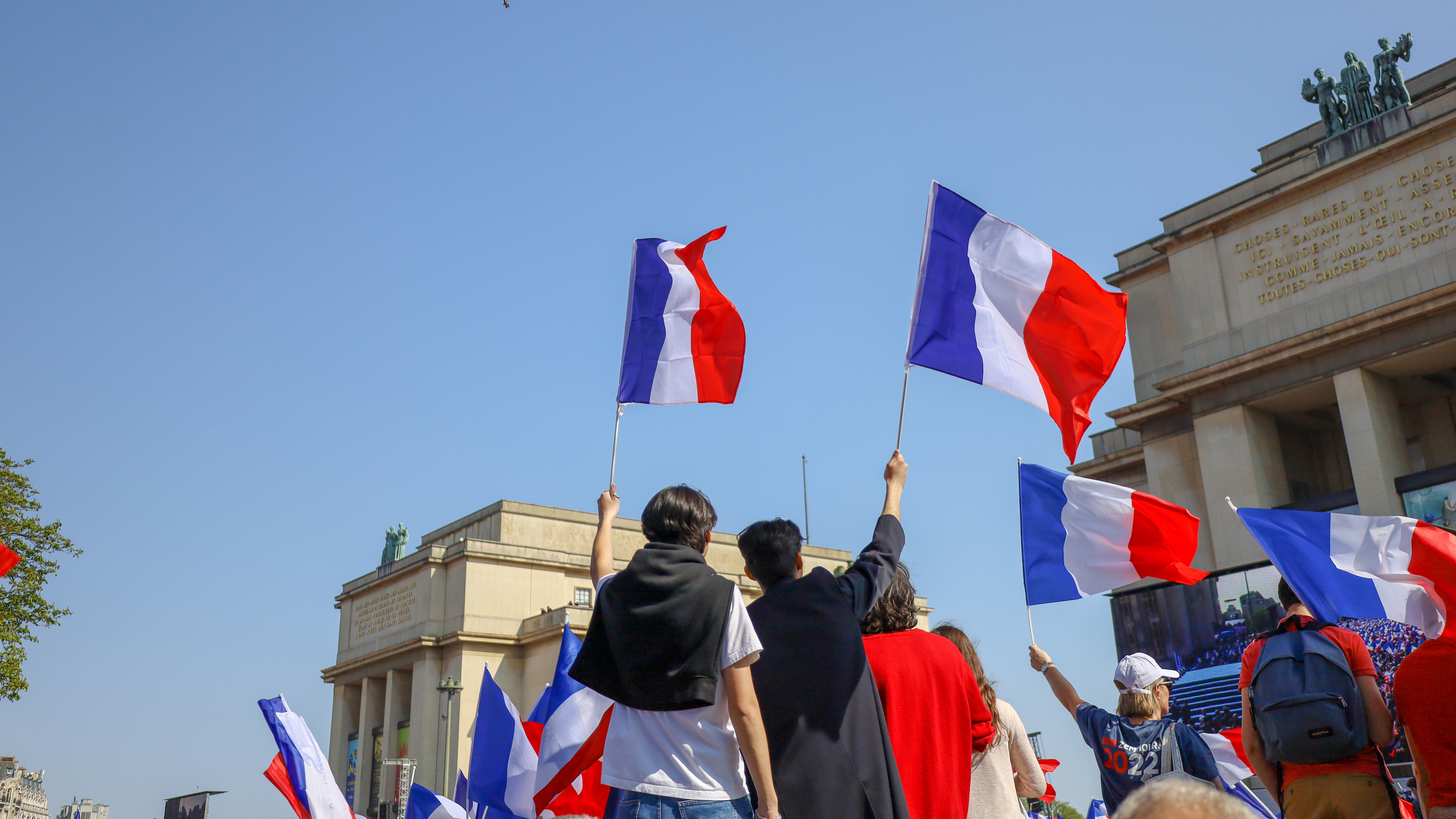 Беженцы держат флаги Франции, которая предоставляет им убежище