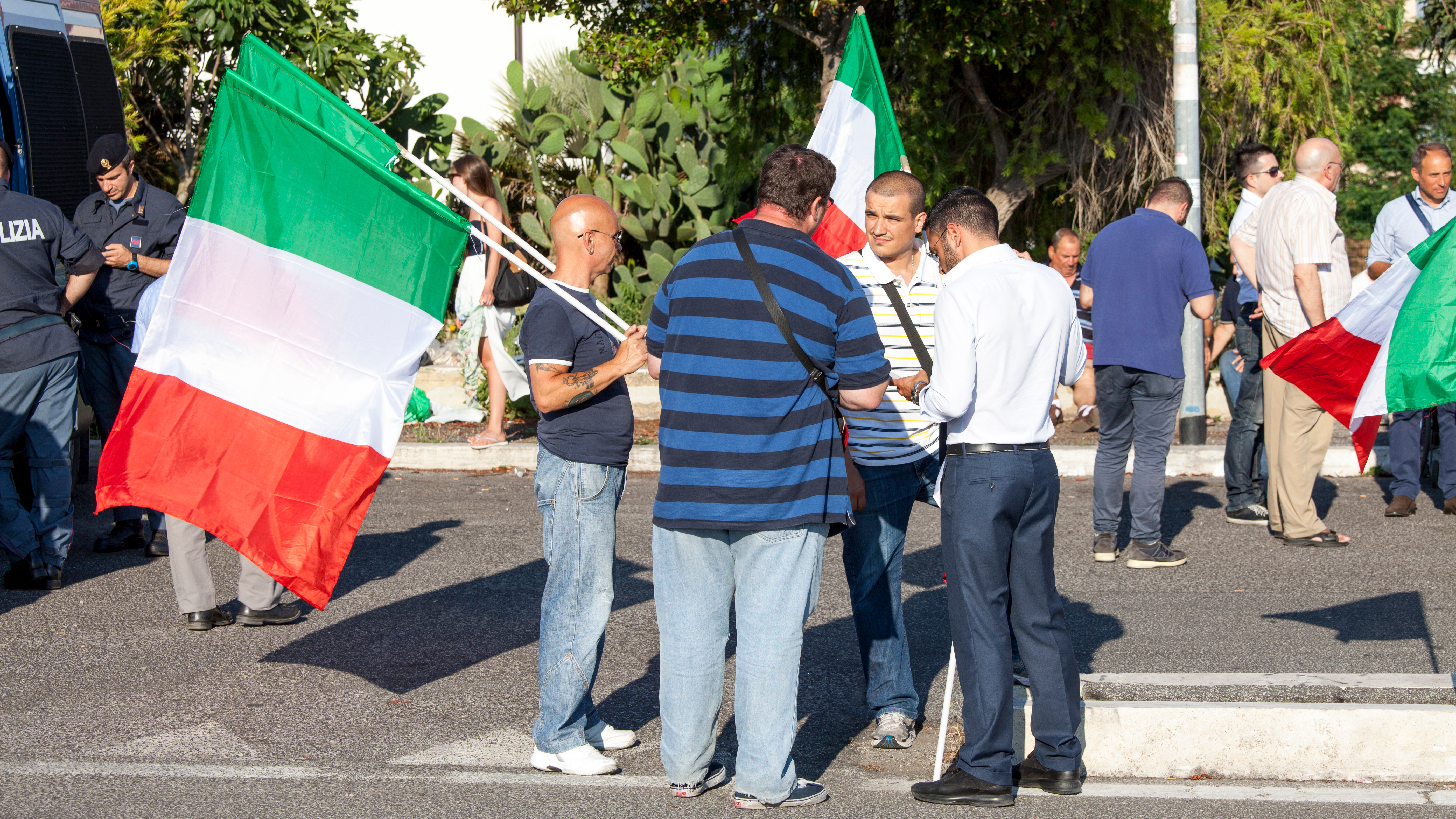Беженцы держат флаги Италии, которая предоставляет им убежище