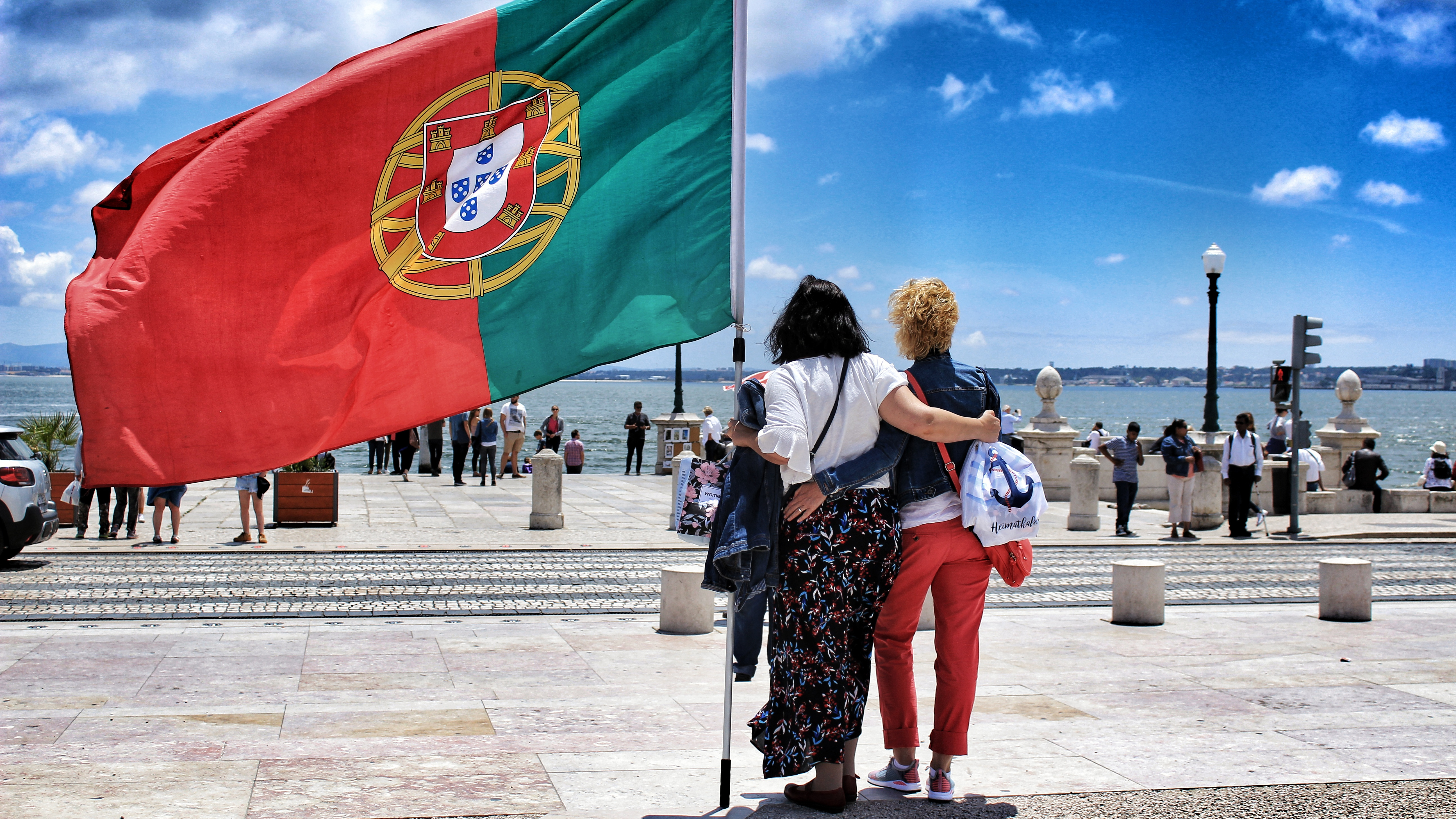 Беженцы держат флаг Португалии, которая предоставляет им убежище