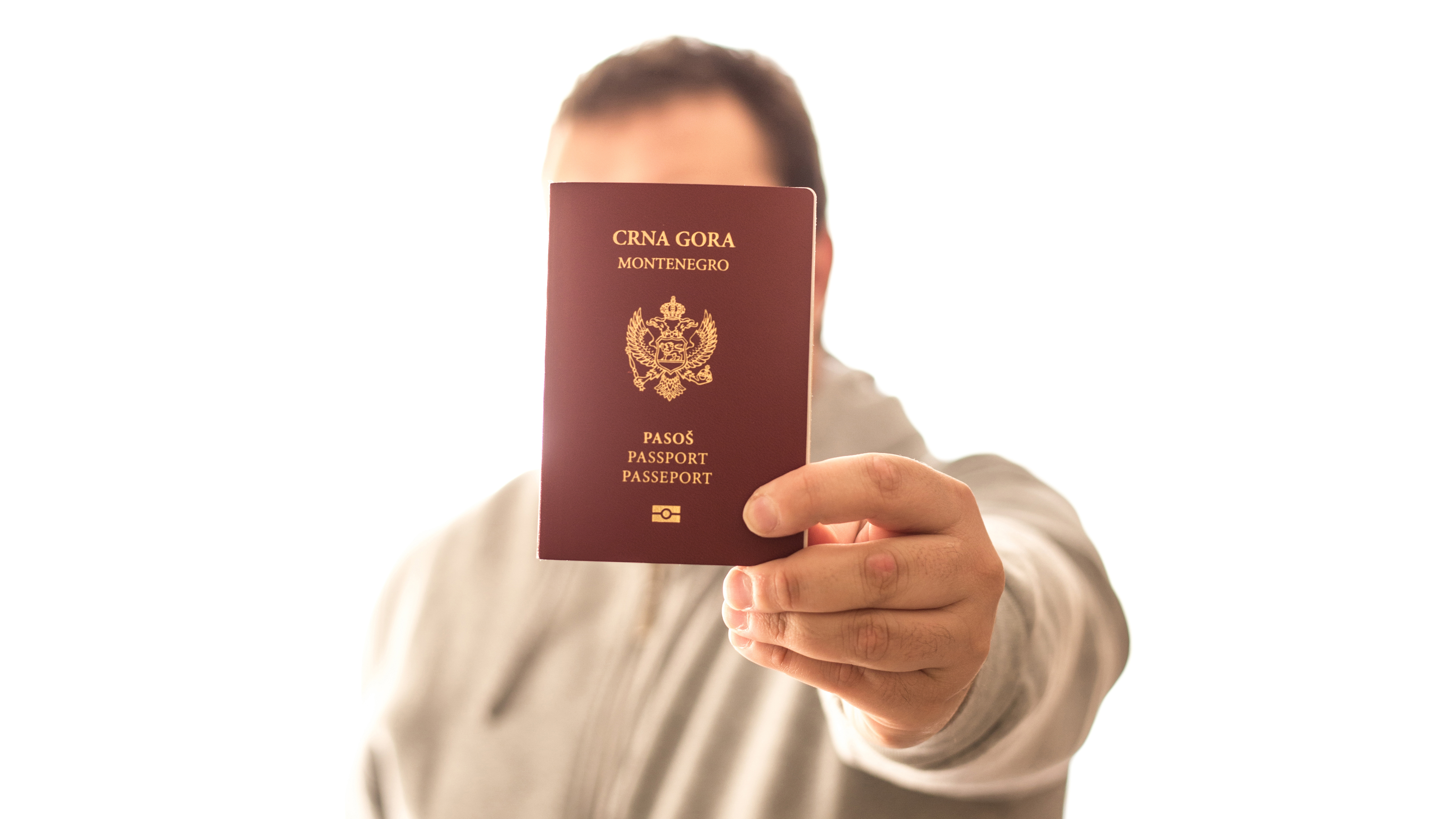 Мужчина держит черногорский паспорт, который он получил в Черногории